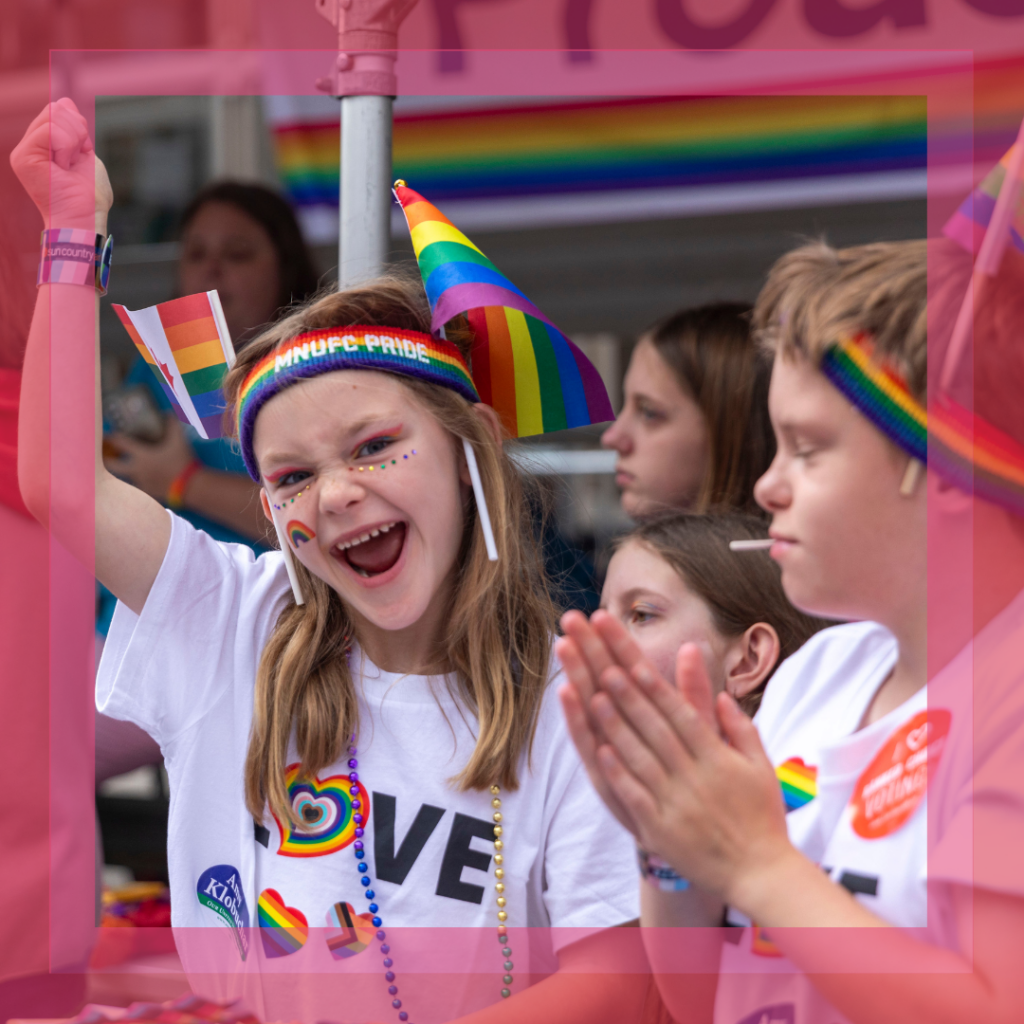 Image of young girl with fist in the air cheering at Pride parade.